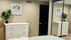 Ein Schlafzimmer mit einem Bett, zwei Nachttischen, einer Kommode, einem Spiegel und zwei an der Wand hängenden Bildern.