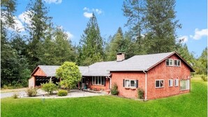 A red brick house with a large front lawn, a garage, and a chimney. - Rainier Estates' 5 Acre, 3100sqft, HotTub, Events (Elbe)