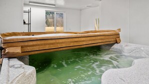 A hot tub with a wooden edge, surrounded by stone walls, in a room with a window and a door. - Rainier Estates' 5 Acre, 3100sqft, HotTub, Events (Elbe)