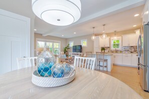 Una cocina amplia con armarios blancos, una isla central e iluminación colgante.