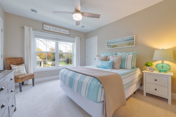 Un dormitorio con cama, mesita de noche y ventana con cortinas.