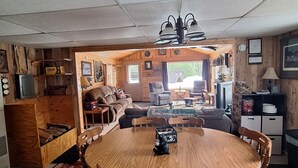L’intérieur chaleureux d’un chalet avec une table à manger en bois, des chaises, un canapé et une cheminée.
