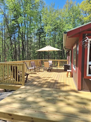 A wooden deck with outdoor furniture, a table, and an umbrella.