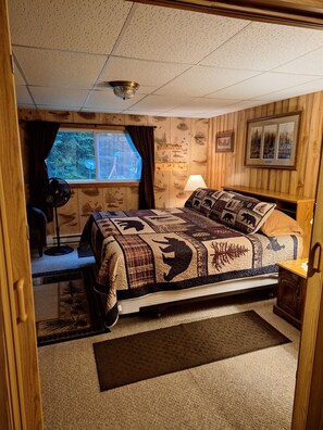 Ein Schlafzimmer mit einem Bett, einem Schreibtisch, einer Lampe und einem Fenster mit Vorhängen.
