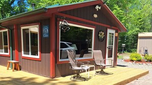 Une petite cabane dotée d’une véranda, de sièges extérieurs et d’une enseigne indiquant qu’il s’agit d’une cabane.