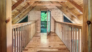 A wooden interior with a sloped ceiling and a central door leading outside.