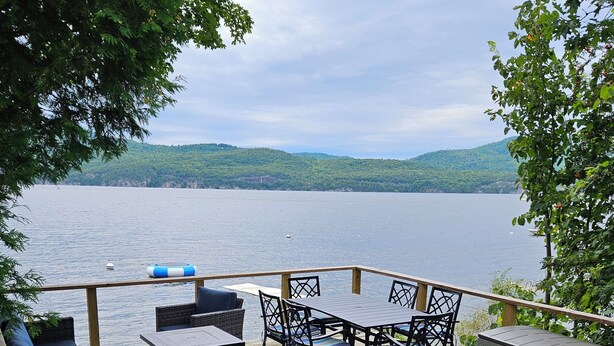 A deck with outdoor furniture overlooking a lake, surrounded by trees and hills. - Willsboro Relaxing Waterfront Getaway (Willsboro)