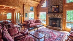A log cabin interior with a fireplace, wooden furniture, and large windows. - Crazy Like a Fox Log Cabin | 2 Huge Decks w/ Incredible Views | Pool Table & Foosball (Sparta)