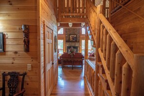 Un interior de madera con una escalera, una chimenea y un sofá al fondo.