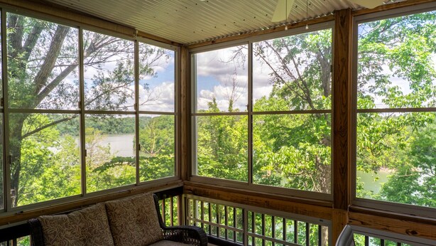 A room with large windows offering a view of a lake surrounded by trees.