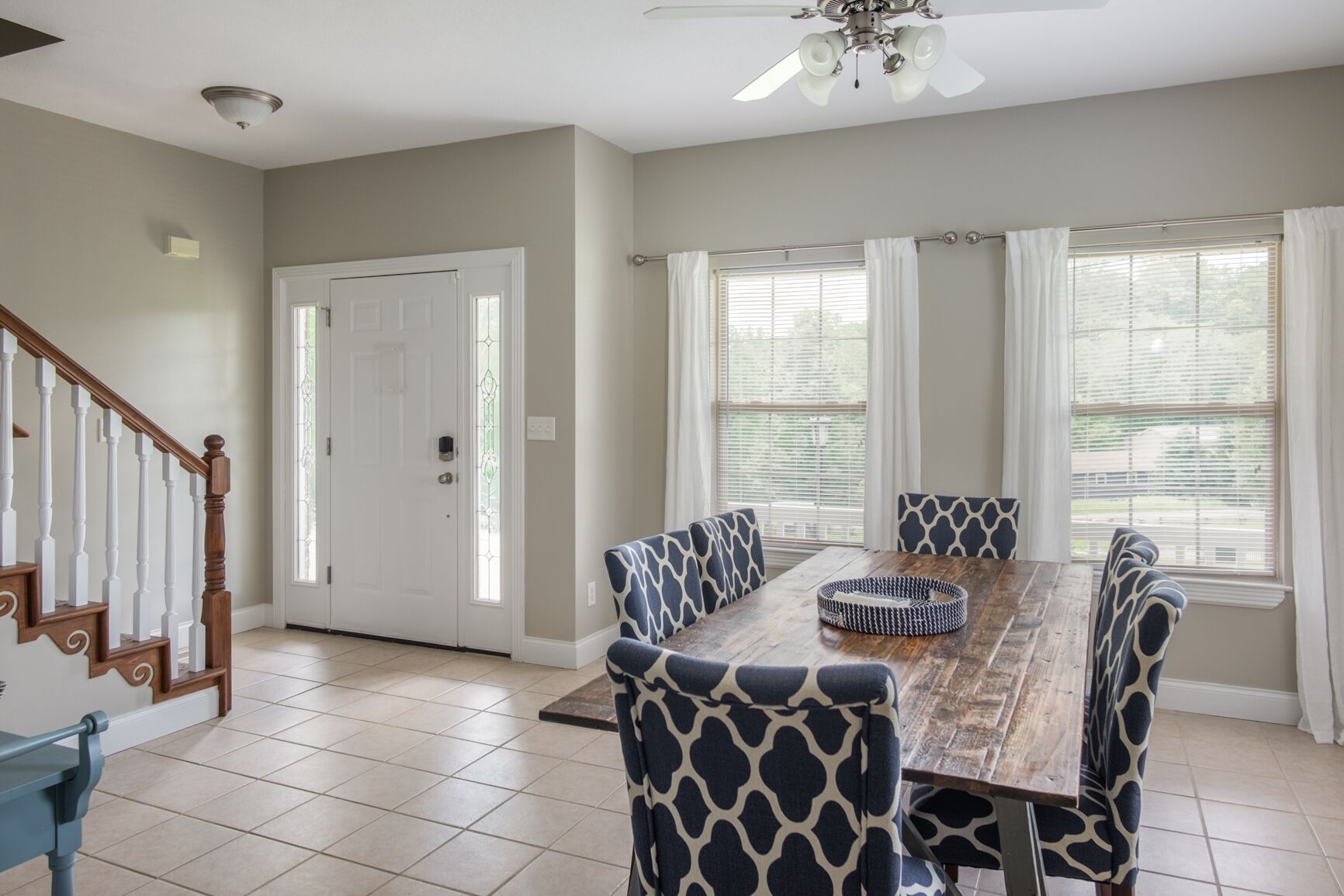 A dining area with a wooden table, patterned chairs, and a ceiling fan.