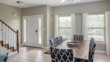 A dining area with a wooden table, patterned chairs, and a ceiling fan.