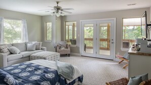 A bedroom with a bed, a chair, a desk, and a sliding glass door leading to a balcony.