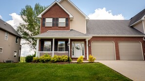 A two-story house with a front porch, garage, and a well-maintained lawn.