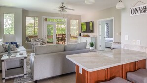 A modern kitchen with a large island, a dining area with a table and chairs, and a cozy seating area with a sofa and cushions.