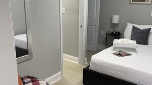 Una camera da letto con un letto, un comodino, una lampada, una ventola a soffitto e uno specchio.