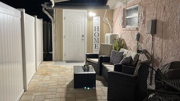 Relax in our inviting patio area, featuring a comfortable wicker sofa and chair, perfect for taking in the view from the window.