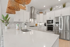 Modern kitchen with a large island, stainless steel sink, and stovetop.