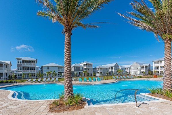 Relax by the pool surrounded by palm trees and lounge chairs.