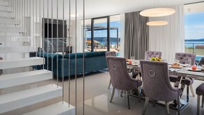 Ein modernes Interieur mit Essbereich, Treppe und Meerblick.