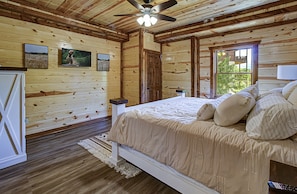 Cozy bedroom with a single bed, television, and window offering a view of the outdoors.