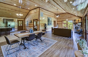 Cozy living area with a large dining table and comfortable seating, a modern kitchen, and a fireplace.