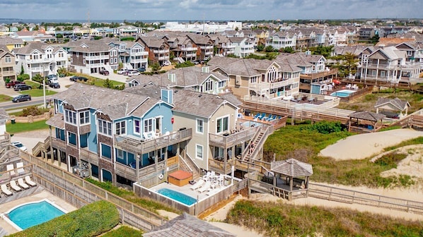 Zona residencial à beira-mar, com casas que possuem varandas, piscina e um caminho de acesso à praia.