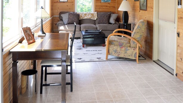 A wooden interior with a ceiling fan, a sofa, a dining table, and chairs.