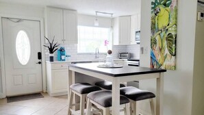 A kitchen with white cabinets, a black countertop, and a bar stool.
