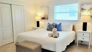 A bedroom with a bed, nightstands, a bench, and a ceiling fan.