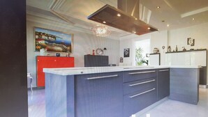 A modern kitchen with a central island, a red cabinet, and a clock on the wall.