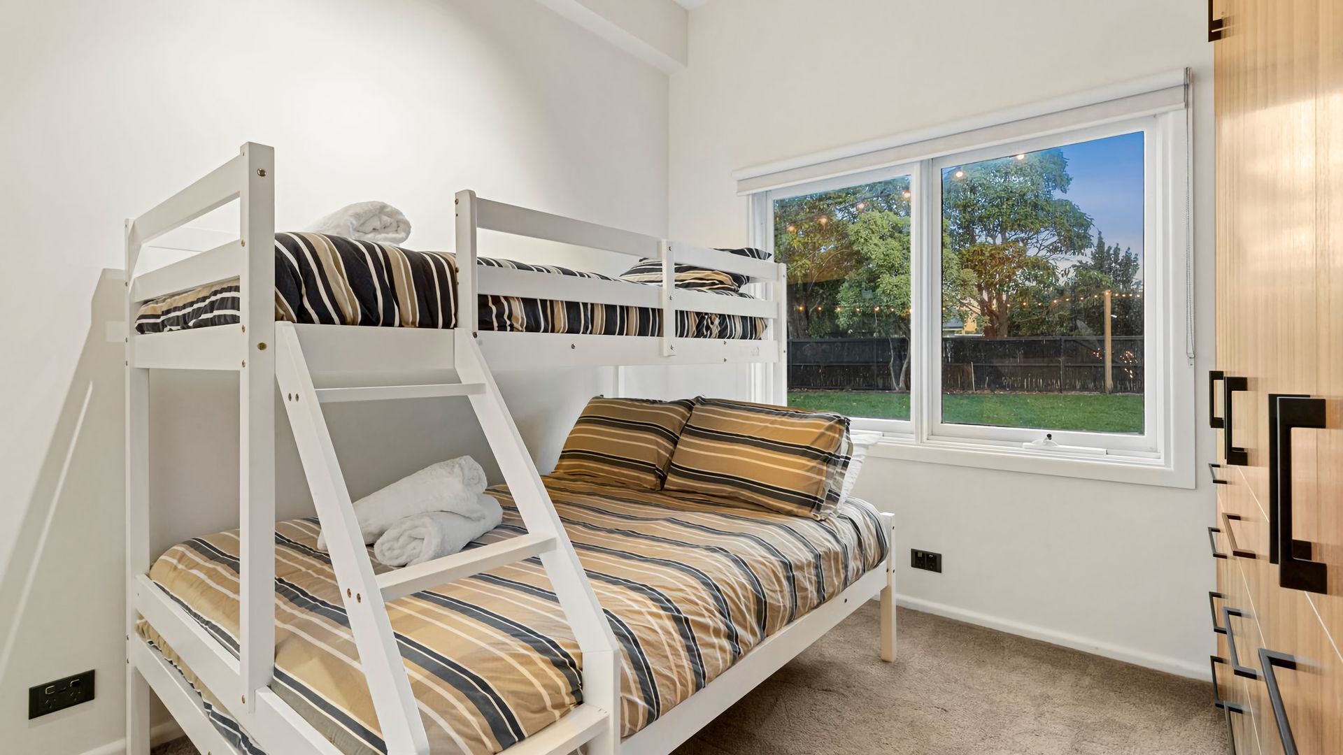 A bunk bed room with a window and a built-in wardrobe.