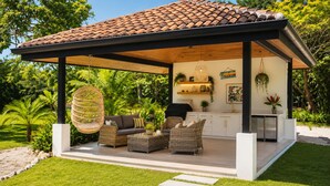 A covered outdoor seating area with wicker furniture, a hanging light fixture, and a kitchen area with white cabinets and a hanging plant. - 2 min walk private  path to the beach . Beach club . Daily maid . Free ATVs  (Hacienda pinilla)