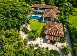 A modern two-story house with a swimming pool, surrounded by lush greenery. - 2 min walk private path to the beach . Beach club . Daily maid . Free ATVs (Hacienda pinilla)