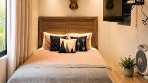 A bedroom with a large bed, a wooden headboard, a wall-mounted bull's head sculpture, a mirror, and a bedside table with a fan. - 2 min walk private  path to the beach . Beach club . Daily maid . Free ATVs  (Hacienda pinilla)