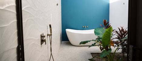 Een moderne badkamer met een vrijstaand bad, een douche en een plant.