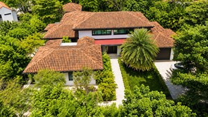 A two-story house with a tiled roof, surrounded by lush greenery and a pathway leading to the entrance. - 2 min walk private  path to the beach . Beach club . Daily maid . Free ATVs  (Hacienda pinilla)