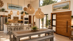 A modern kitchen with a central island, pendant lighting, and a dining area with a bench.