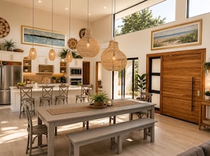 A modern kitchen with a central island, pendant lighting, and a dining area with a bench.