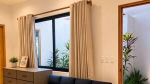 A modern living room with a sofa, a wooden cabinet, and a window with curtains.