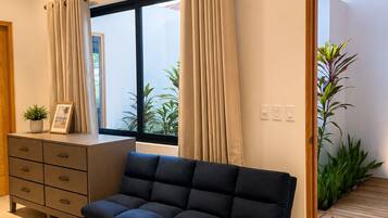 Een moderne woonkamer met een bank, een houten kast en een raam met gordijnen.