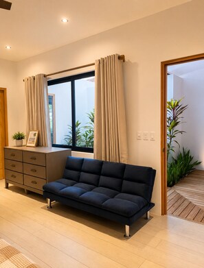 A modern living room with a sofa, a wooden cabinet, and a window with curtains.