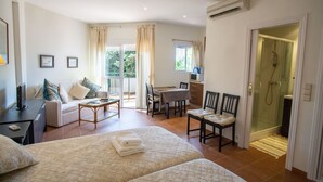 Una habitación de hotel con cama, escritorio, sillón, sofá y zona de ducha.