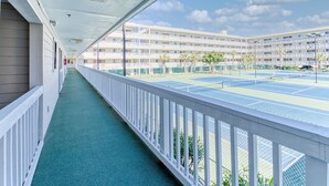 A corridor with a tennis court visible through the railing. - Stylish 2BD/2BA Beach Villa at Hilton Head Resort (Hilton Head Island)