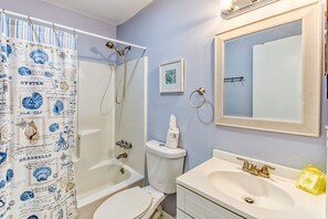 Een badkamer met douche, toilet, wastafel en spiegel.