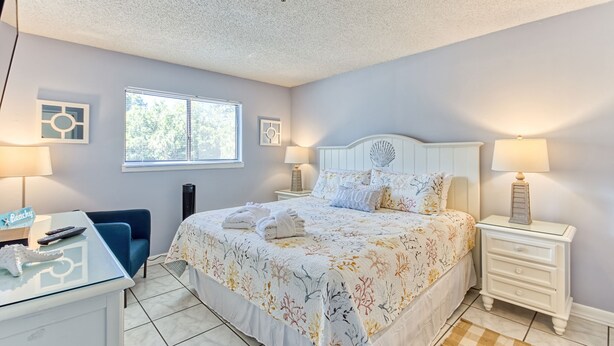 A bedroom with a bed, bedside tables, a desk, and a chair. - Stylish 2BD/2BA Beach Villa at Hilton Head Resort (Hilton Head Island)