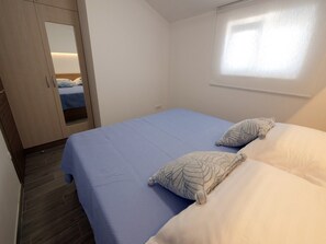 A bedroom with a bed, two pillows, a wardrobe, and a window.