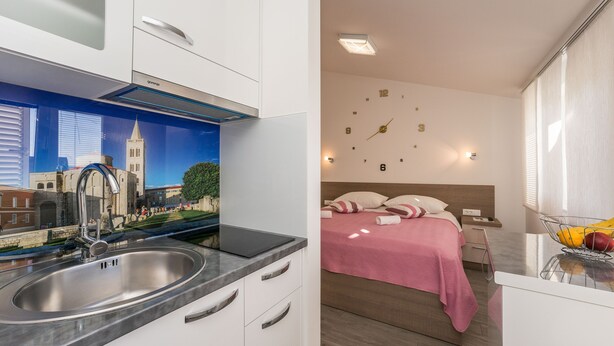Een moderne keuken met een spoelbak van roestvrij staal en een muurschildering van een stadsgezicht.