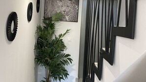 Una escala de disseny modern, una planta en test i una obra d'art emmarcada a la paret.