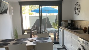 Una cuina moderna amb zona de menjador, grans finestres i una rentadora.
